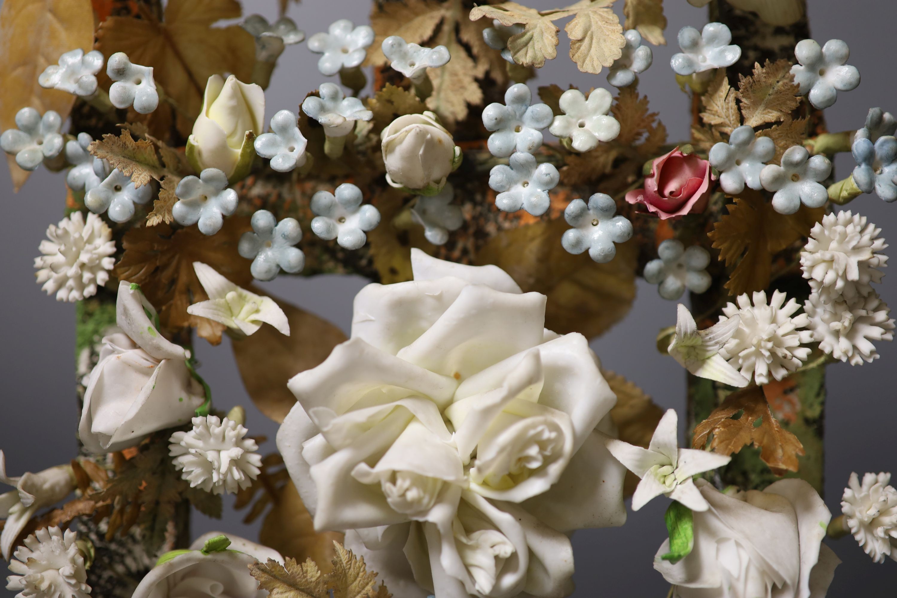 A late 19th century model of porcelain flowers under a glass dome 52cm total height